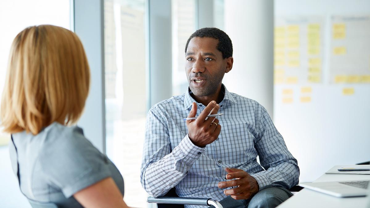 Man talking to woman in a meeting room.